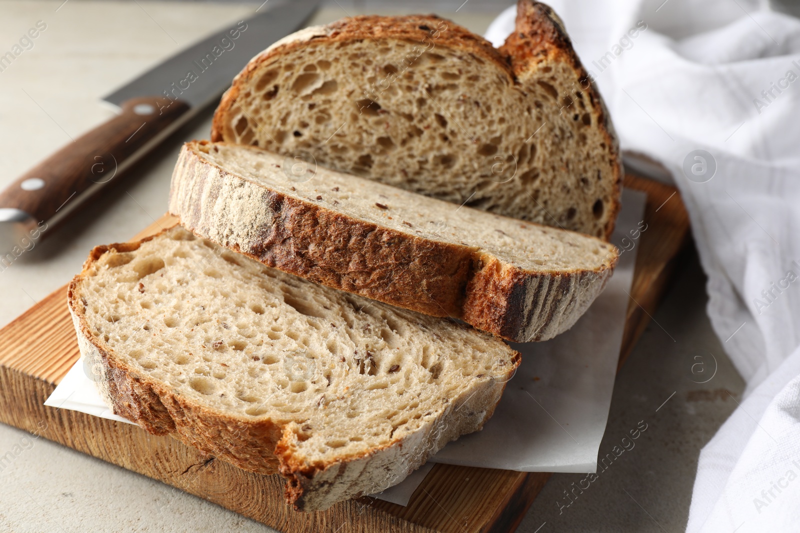 Photo of Cut loaf of fresh bread and knife on table, closeup