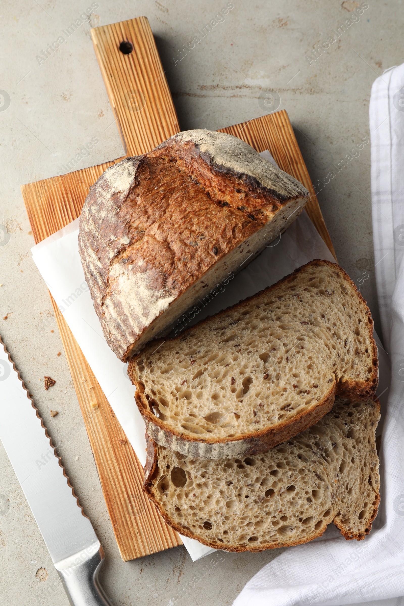 Photo of Cut loaf of fresh bread and knife on table, top view