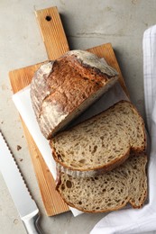 Photo of Cut loaf of fresh bread and knife on table, top view