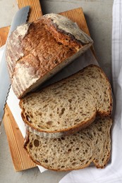 Photo of Cut loaf of fresh bread and knife on table, top view