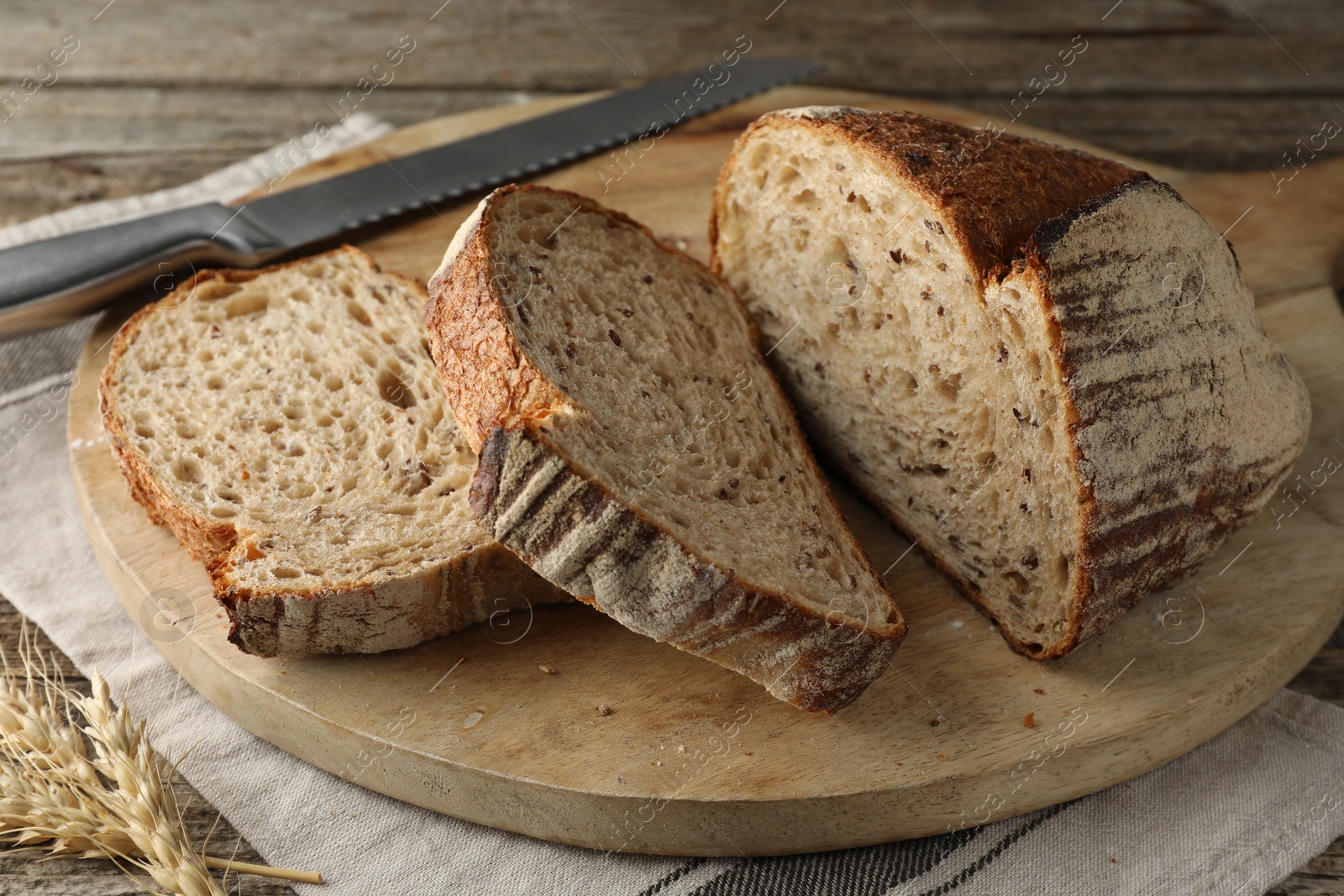 Photo of Cut loaf of fresh bread and knife on wooden table, closeup