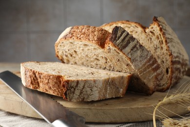 Cut loaf of fresh bread and knife on table, closeup