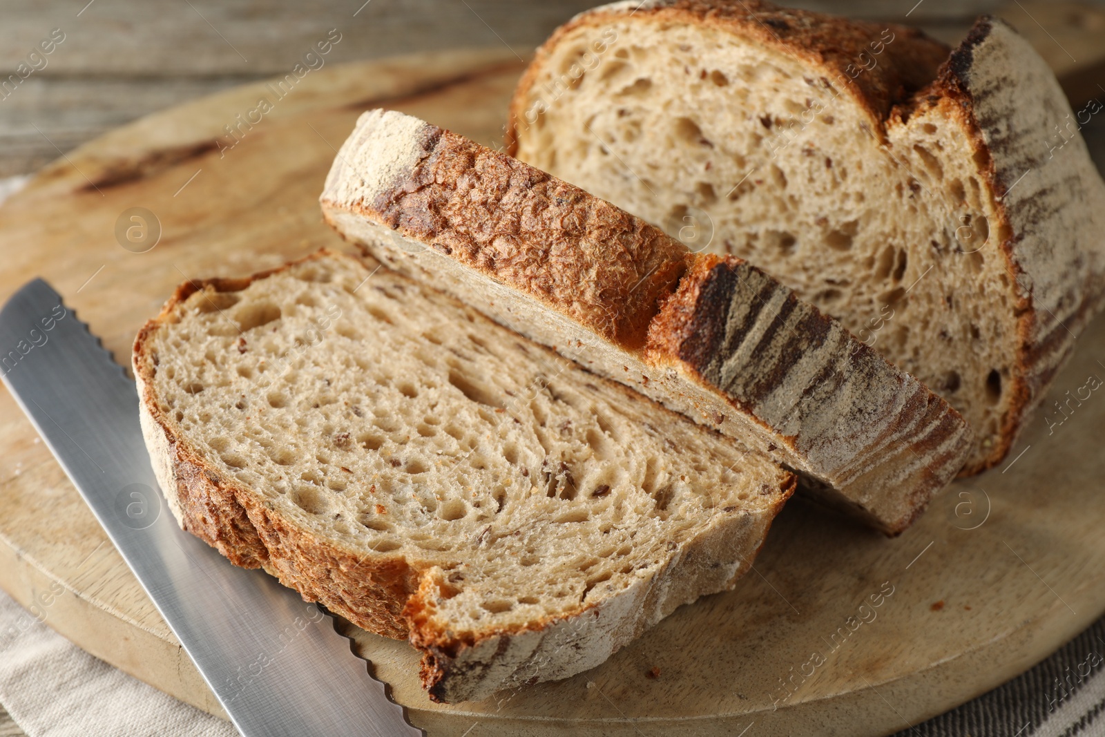 Photo of Cut loaf of fresh bread and knife on table, closeup