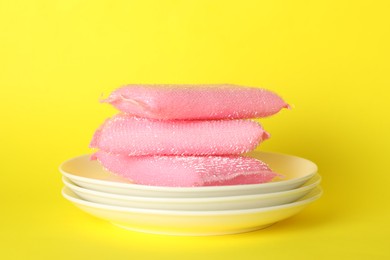 Photo of Stack of sponges and plates on yellow background, closeup