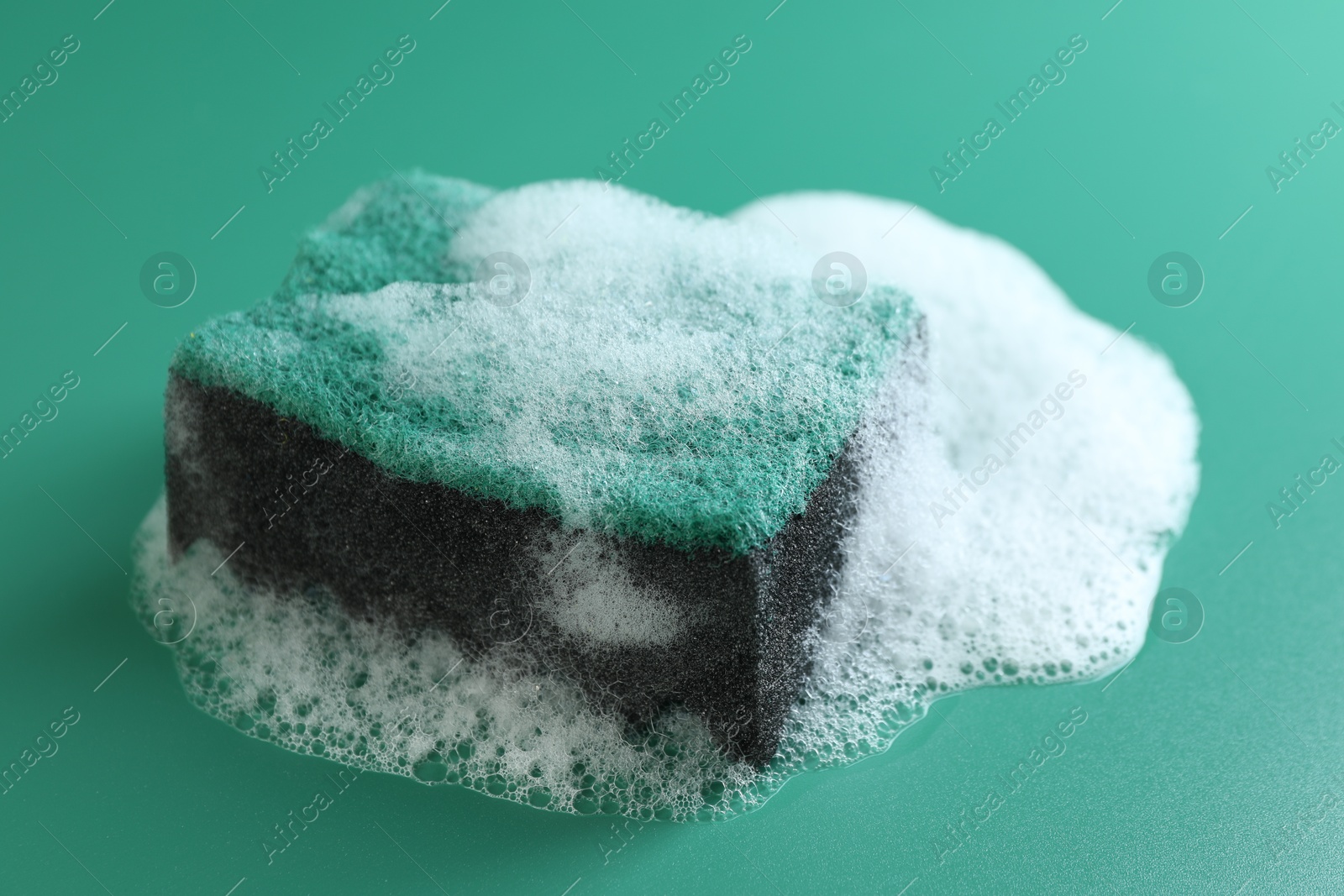 Photo of One sponge in foam on green background, closeup