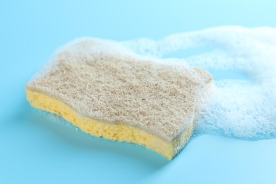 Photo of One sponge with foam on light blue background, closeup