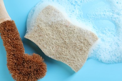 Photo of One sponge with foam and brush on light blue background, flat lay