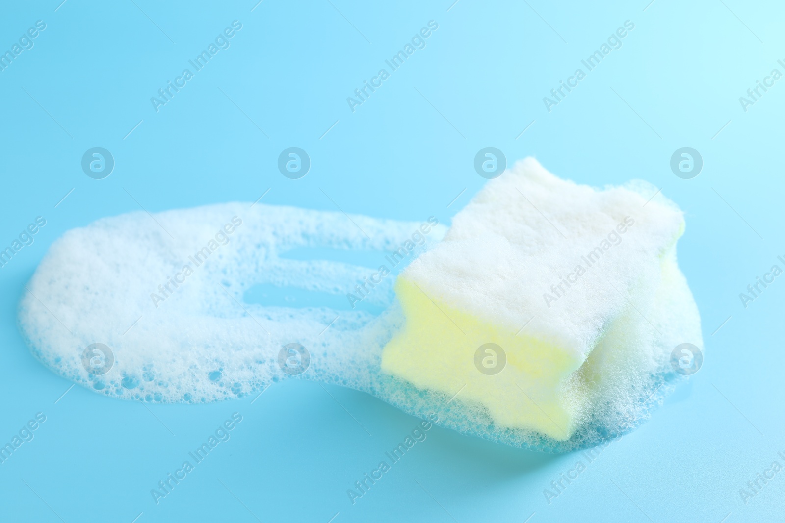 Photo of One sponge with foam on light blue background, closeup