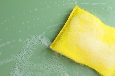 Photo of One sponge with foam on green background, top view. Space for text