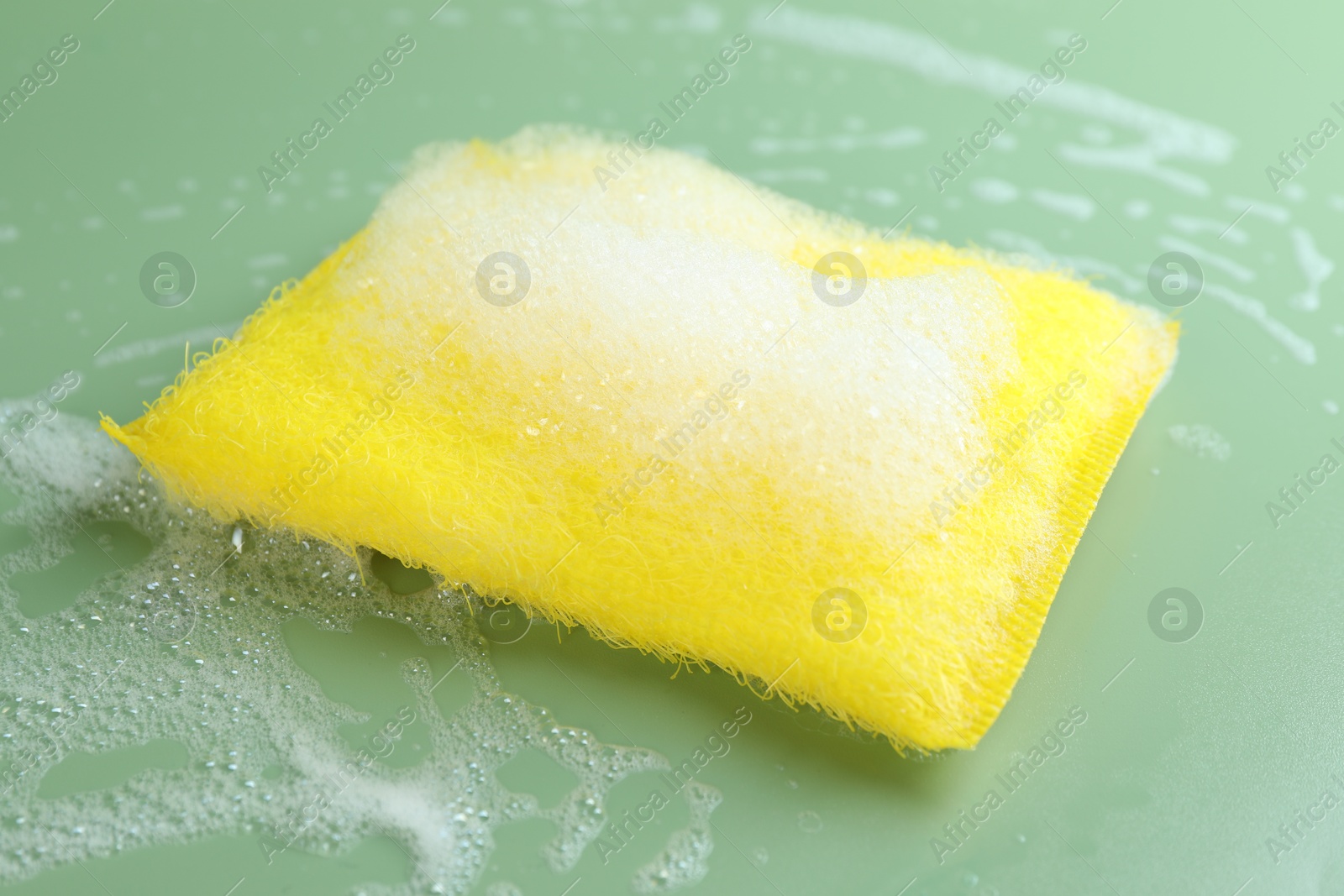 Photo of One sponge with foam on green background, closeup