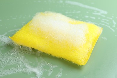 Photo of One sponge with foam on green background, closeup