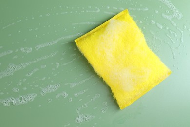 Photo of One sponge with foam on green background, top view. Space for text