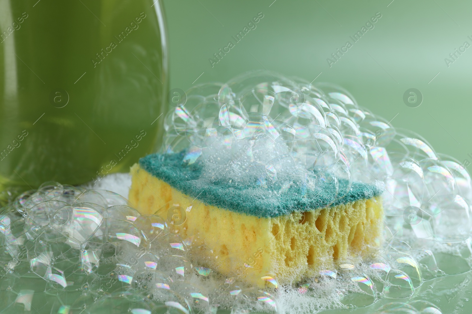 Photo of One sponge with foam and bubbles on green background, closeup