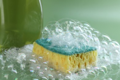 Photo of One sponge with foam and bubbles on green background, closeup