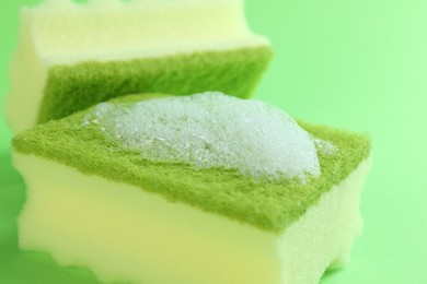 Photo of Sponges with foam on green background, closeup