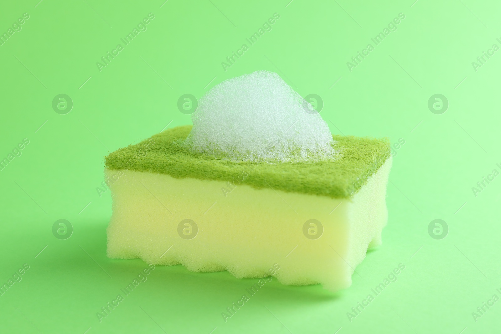 Photo of One sponge with foam on green background, closeup