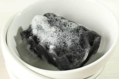 Photo of Sponge with foam and stack of bowls, closeup