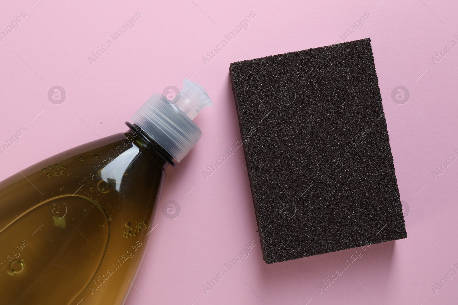 Photo of Sponge and bottle with detergent on pink background, flat lay