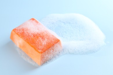 Photo of One sponge with foam on light blue background, closeup