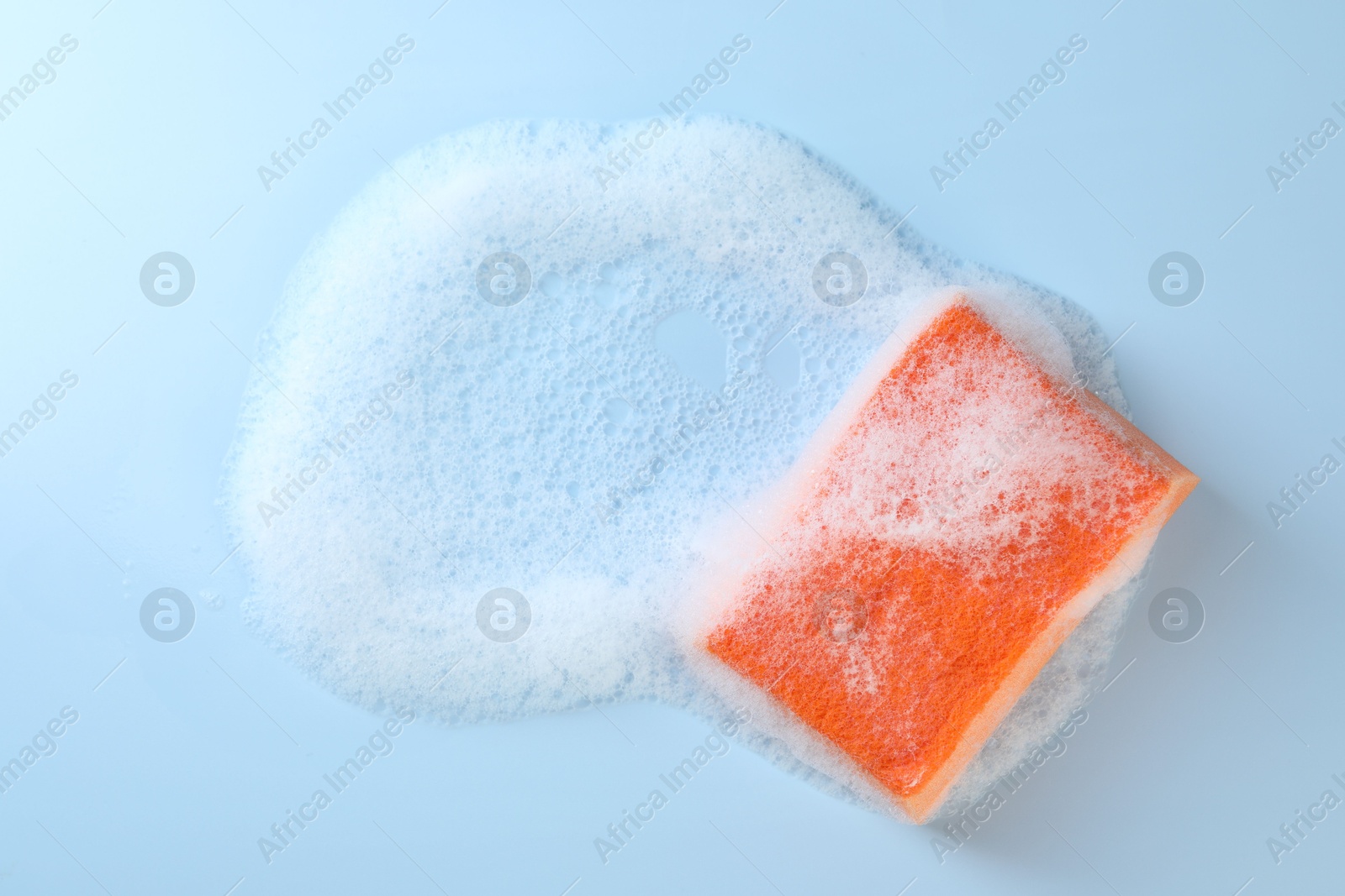 Photo of One sponge with foam on light blue background, top view