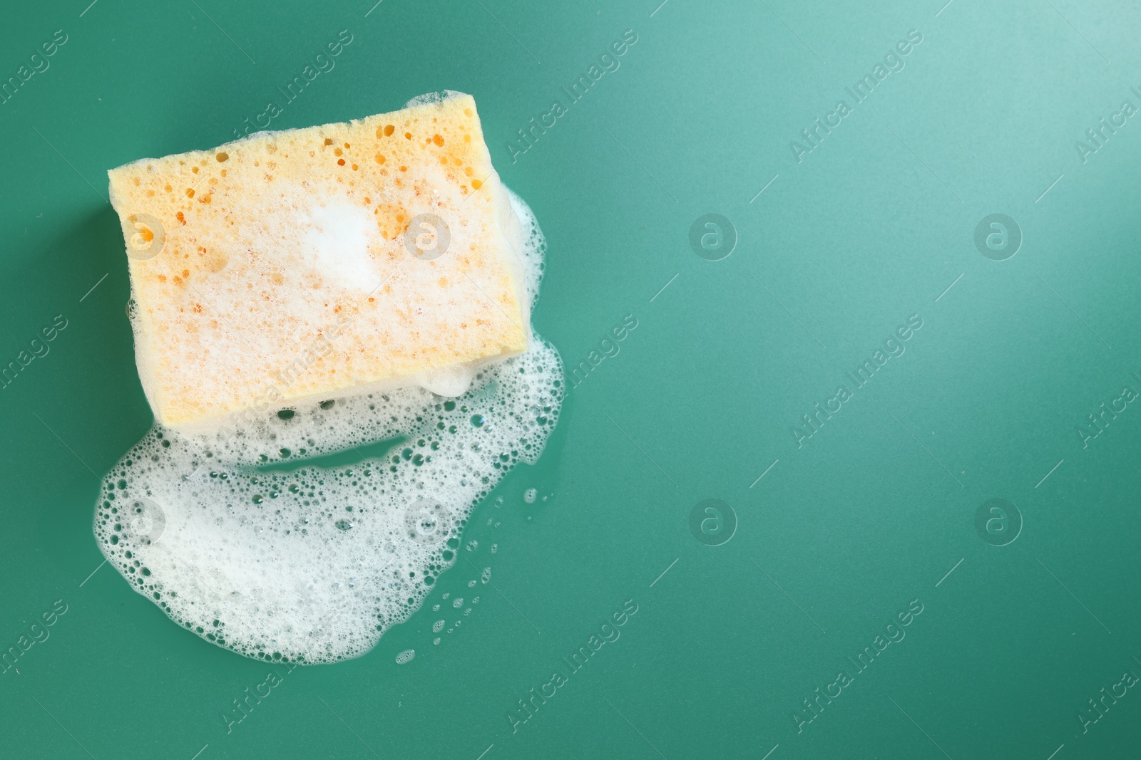 Photo of Sponge with foam on green background, top view. Space for text