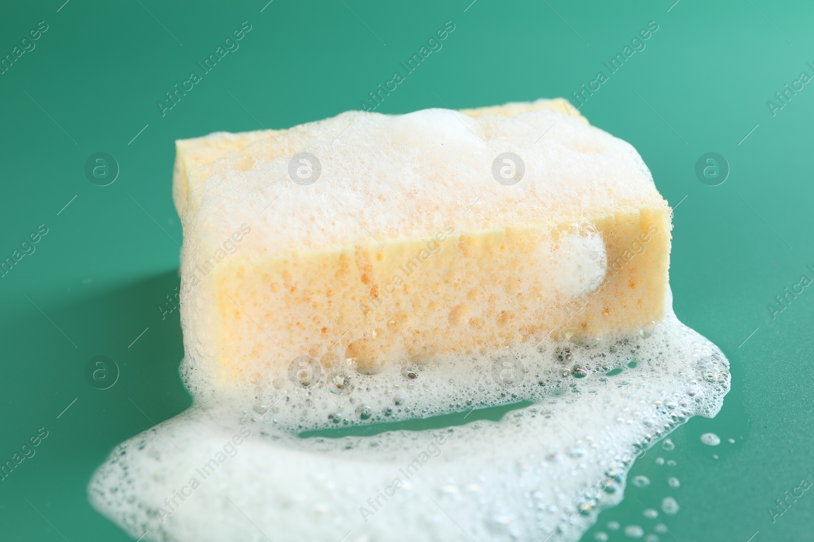 Photo of Sponge with foam on green background, closeup