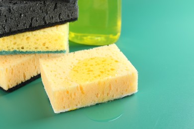 Photo of Sponge with detergent and stack of ones on green background, closeup