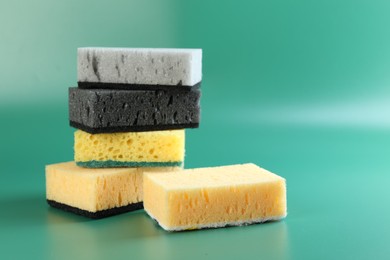 Photo of Different sponges on green background, closeup. Space for text