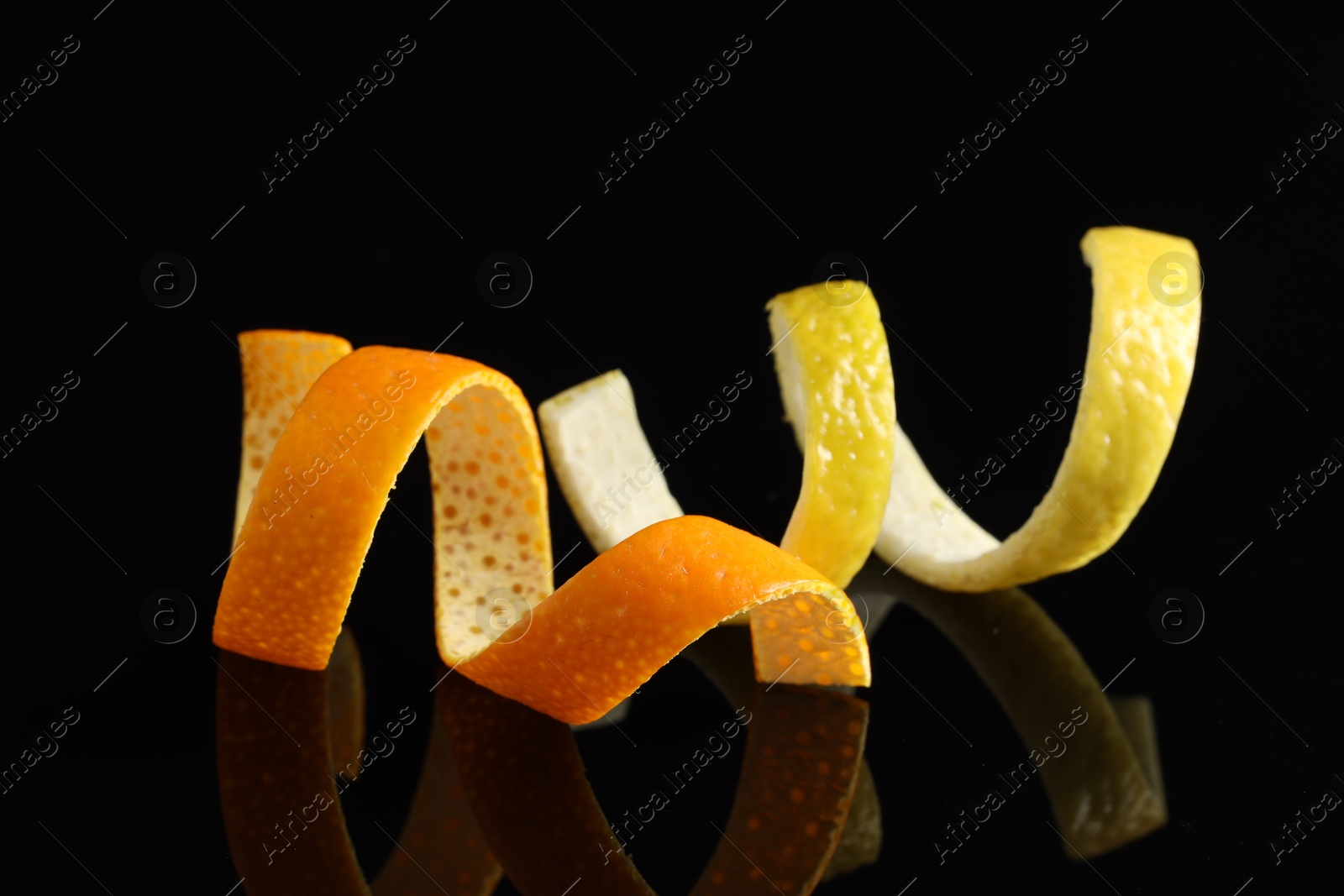 Photo of Lemon and orange peels on black mirror surface, closeup