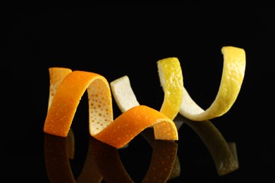 Photo of Lemon and orange peels on black mirror surface, closeup