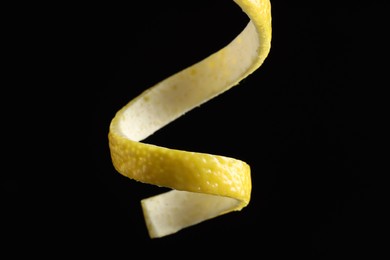 Photo of One curly lemon peel on black background, closeup