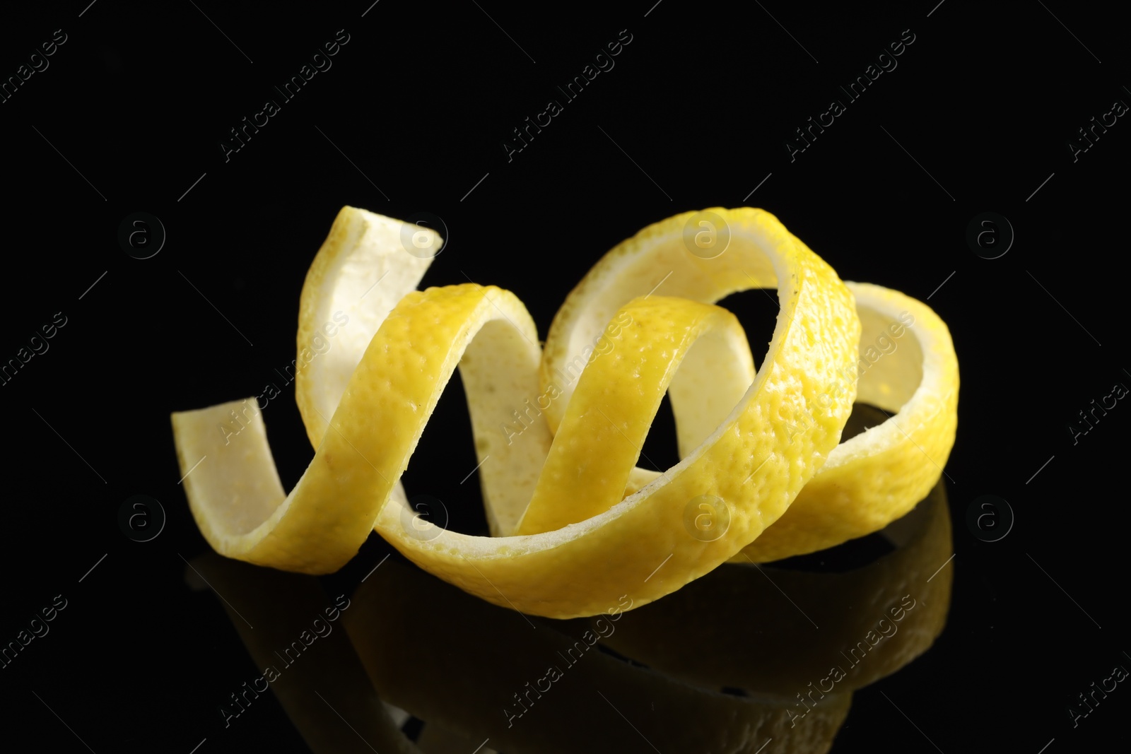 Photo of Curly lemon peels on black background, closeup