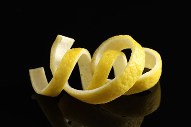 Photo of Curly lemon peels on black background, closeup