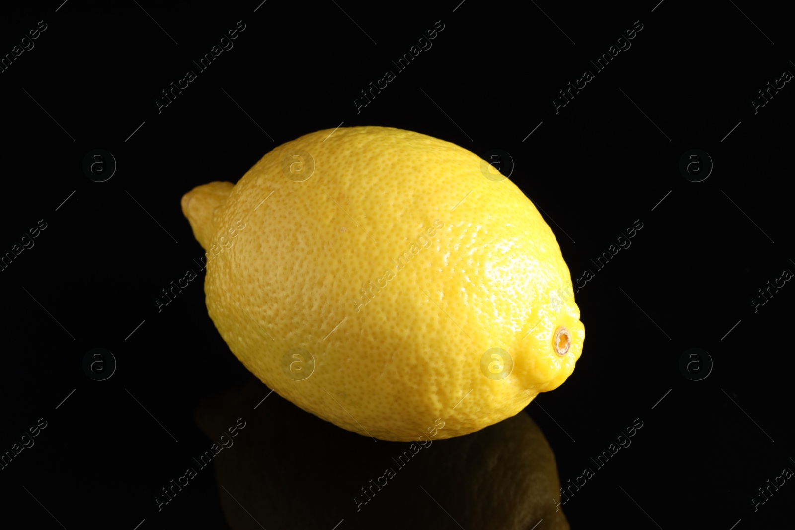 Photo of One fresh lemon on black mirror surface, closeup