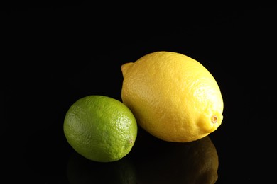 Photo of Fresh lemon and lime on black mirror surface, closeup