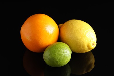 Photo of Fresh orange, lemon and lime on black mirror surface, closeup