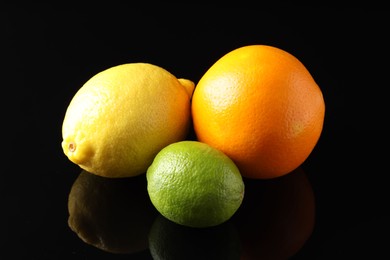 Photo of Fresh orange, lemon and lime on black mirror surface, closeup