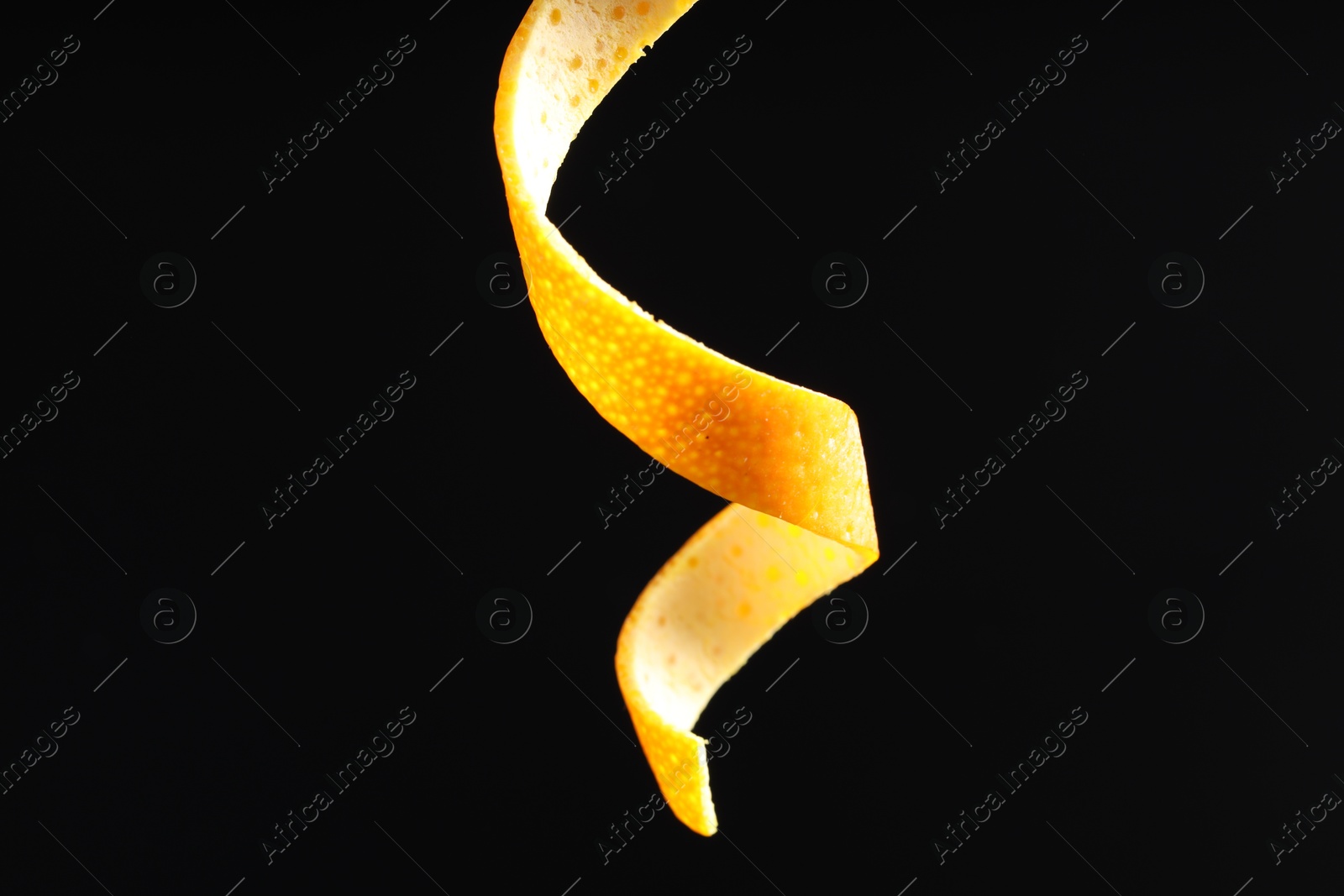 Photo of One curly orange peel on black background, closeup