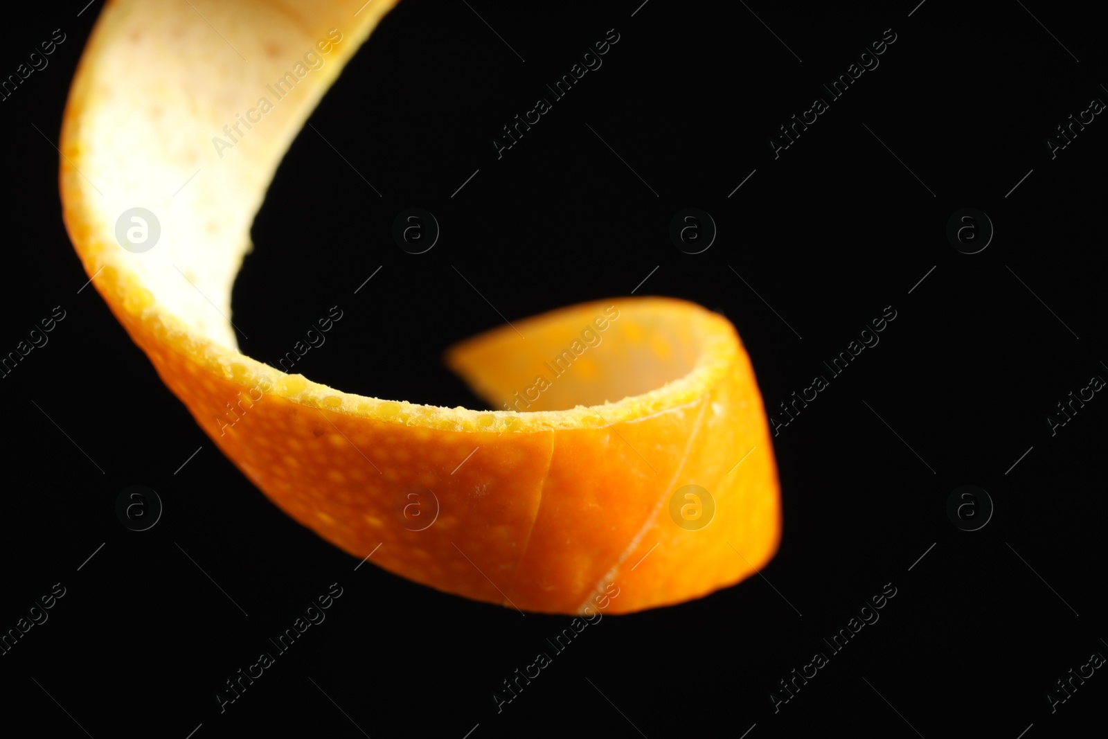 Photo of One curly orange peel on black background, closeup