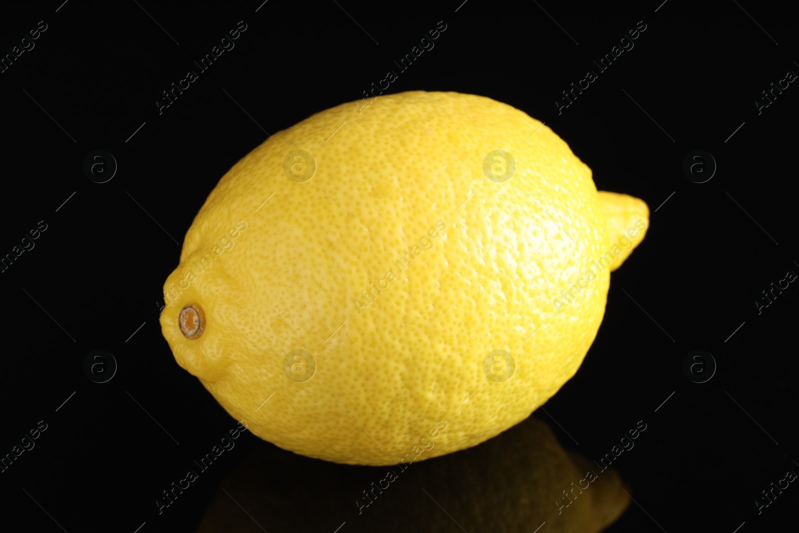 Photo of One fresh lemon on black mirror surface, closeup