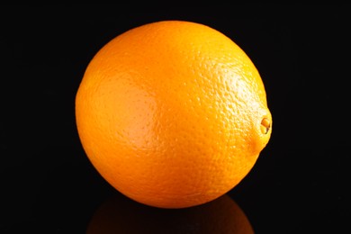 Photo of One fresh orange on black mirror surface, closeup