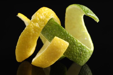 Photo of Lemon and lime peels on black glass surface, closeup