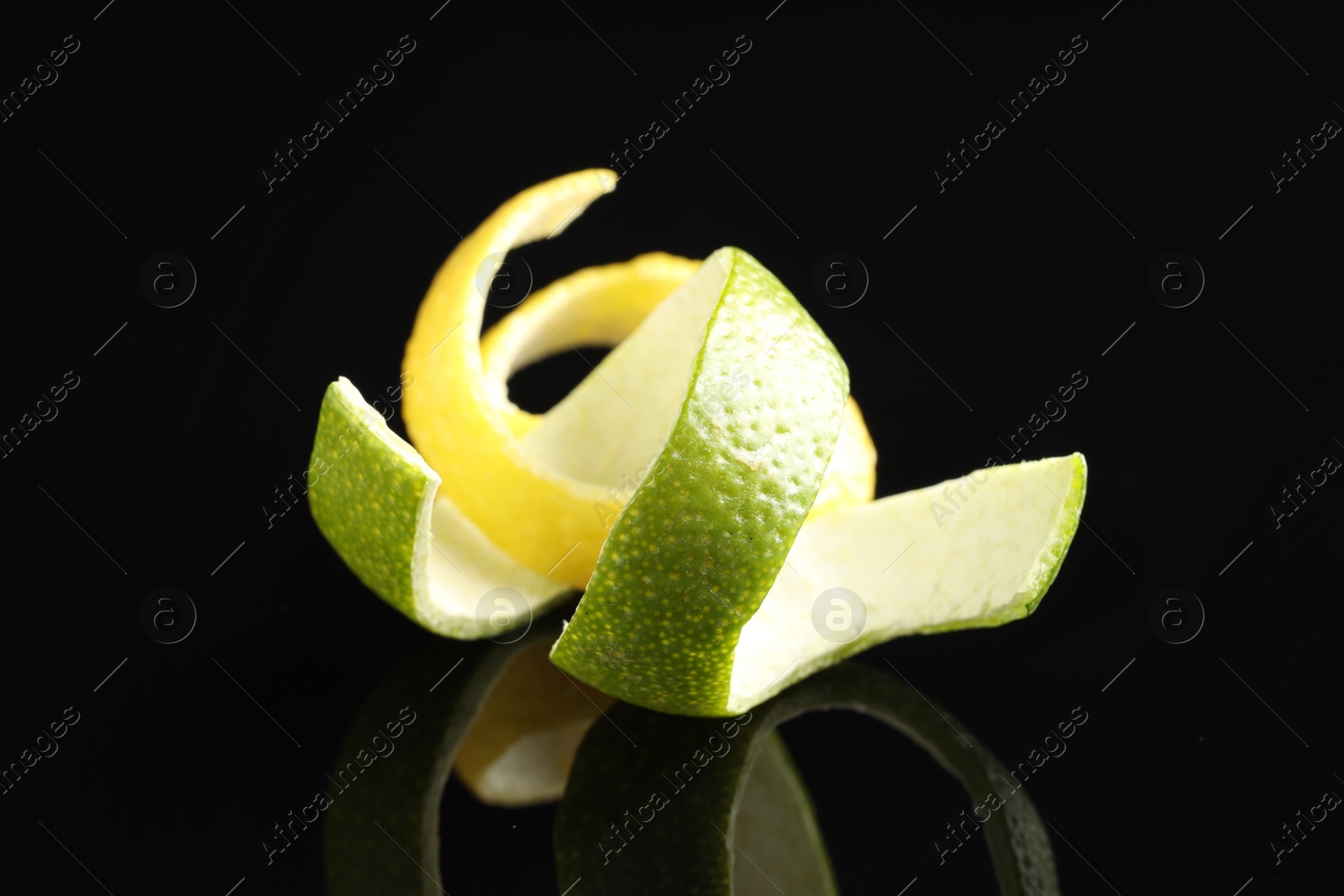 Photo of Lemon and lime peels on black glass surface, closeup