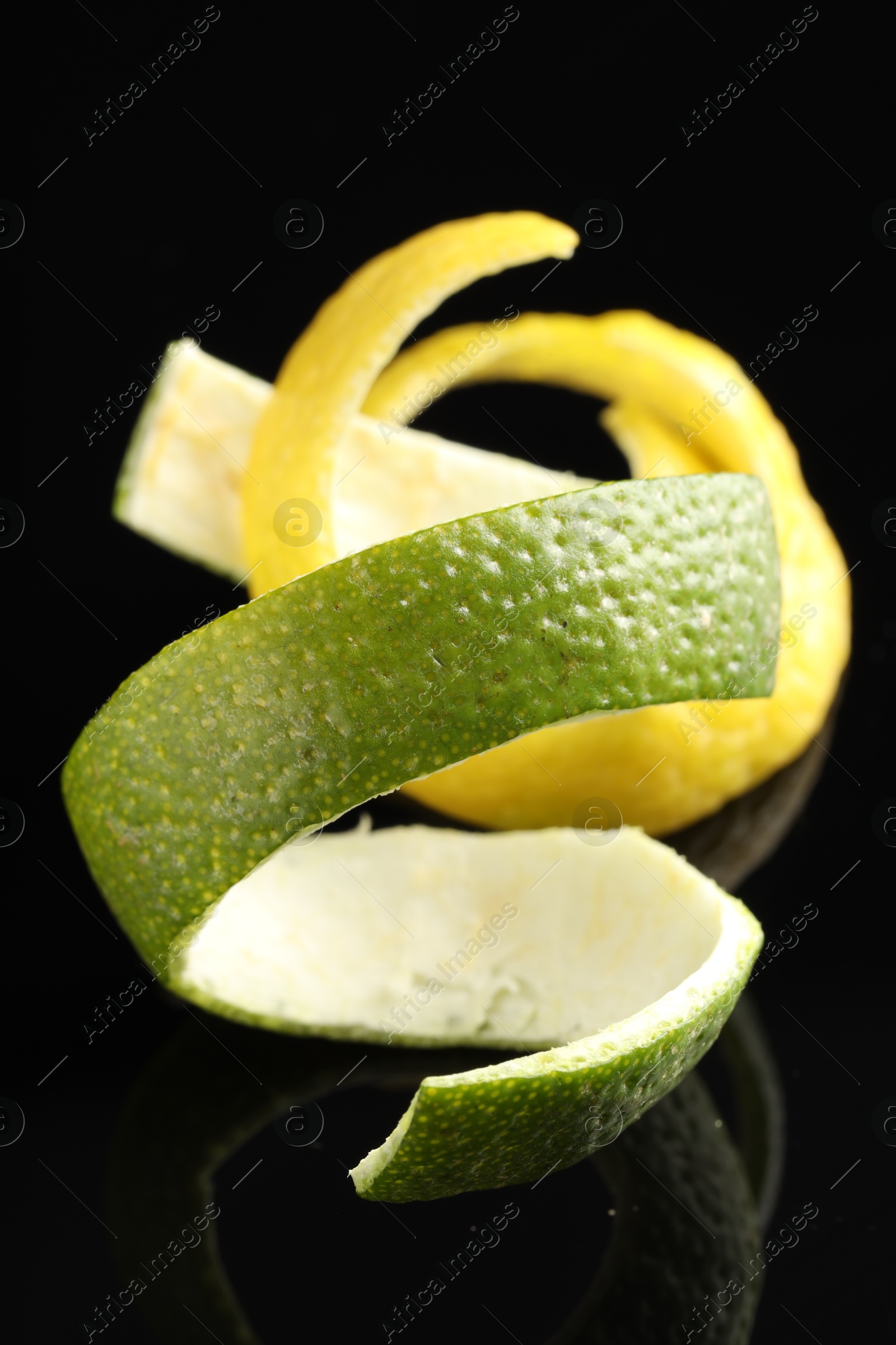 Photo of Lemon and lime peels on black glass surface, closeup