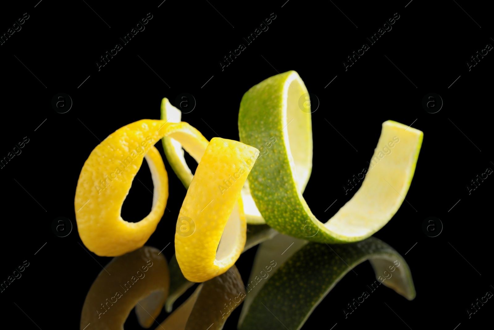 Photo of Lemon and lime peels on black glass surface, closeup