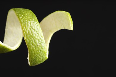 Photo of Fresh lime peel on black background, closeup. Space for text