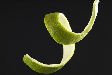 Photo of Fresh lime peel on black background, closeup