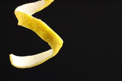 Photo of Fresh lemon peel on black background, closeup. Space for text