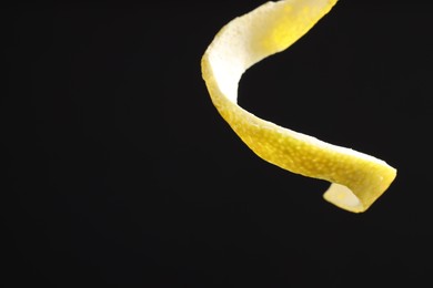 Photo of Fresh lemon peel on black background, closeup. Space for text