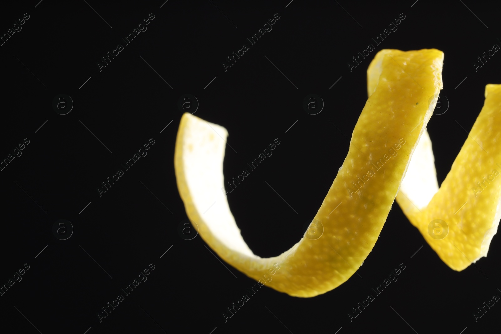 Photo of Fresh lemon peel on black background, closeup. Space for text